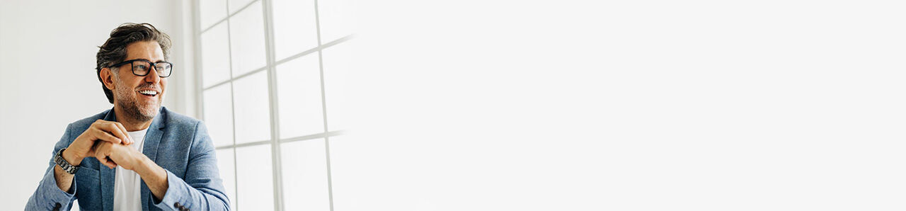 ein Mann in einem blauen Hemd und einer Brille, die an einem Fenster steht